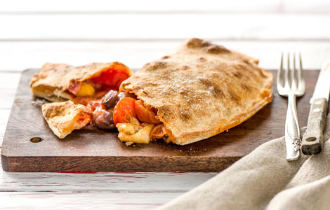 Tony’s Calzone cut in half to show the filling of cheese, tomatoes and other ingredients.
                    Savoury Calzones